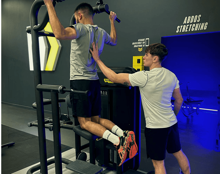  séance d'entrainement dans une salle de sport à Orléans, Simfit soutient et ajuste les mouvements de son client pour plus d'efficacité.