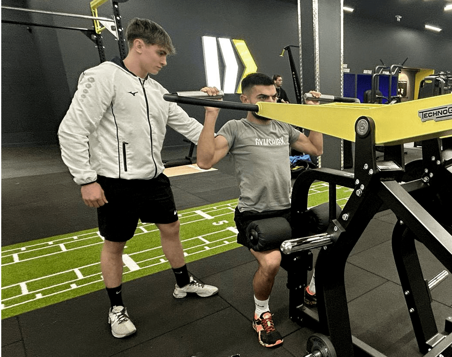 séance de musculation dans une salle de sport Fitnesspark à Orléans. Le coach Simon Ory soutient et accompagne le mouvement de son apprenti.